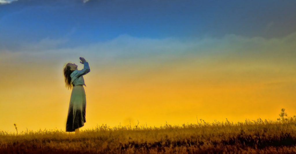 woman prays in a field, prayer, detachment